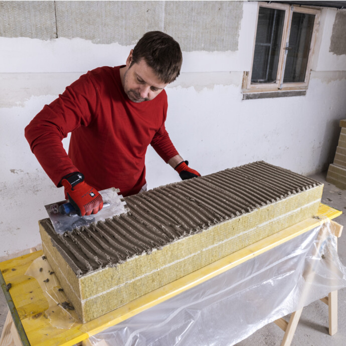 frischen Klebemörtel vollflächig auf der Rückseite der Kellerdeckendämmplatte aus Mineralwolle mit Zahnkelle auftragen.