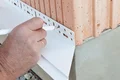 Messung und Markierung der Position einer Putzabschlussleiste an einer Ziegelwand für die nächste Fassadenarbeit.