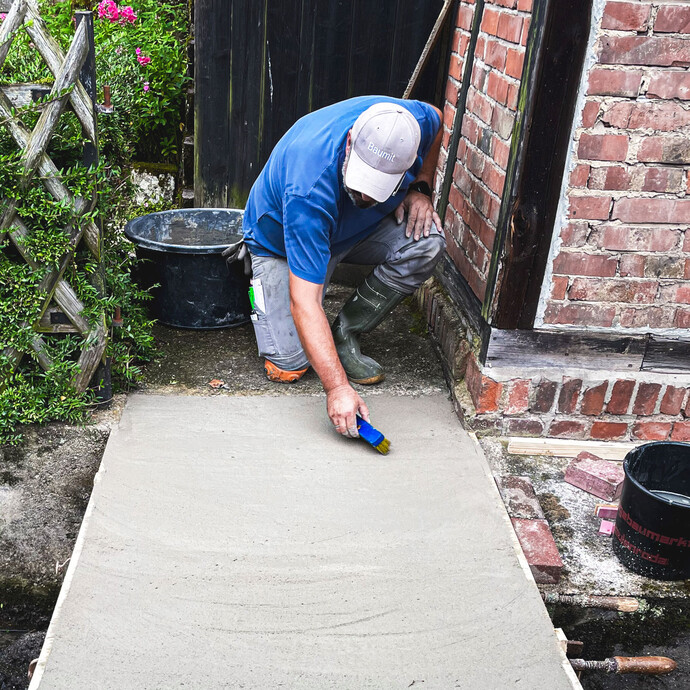 Aufrauen der frischen Betonoberfläche mit Bürste für bessere Haftung.
