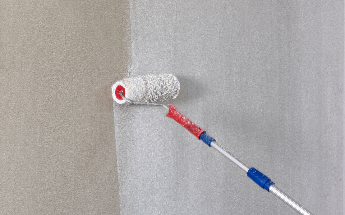 Wand wird mit großer Farbrolle mit weißer Baumit Universalgrundierung grundiert.