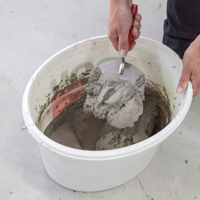 Der Mörtel wird in einem Eimer von Hand angerührt.
