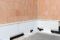 Die Baumit Sockeldämmplatten sind im ersten Schritt entlang des Hauses geklebt.