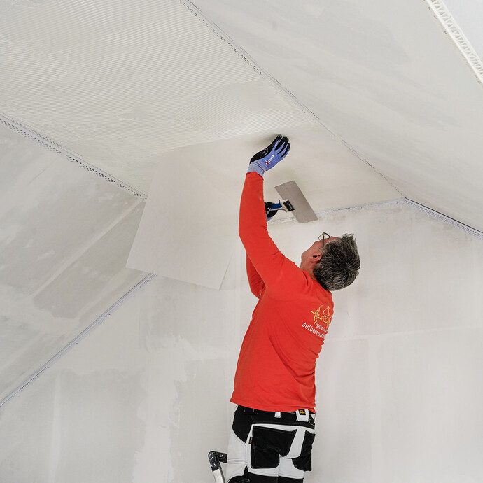 Das Spachtelvlies wird mit einem Flächenspachtel in die feuchte Masse eingedrückt.