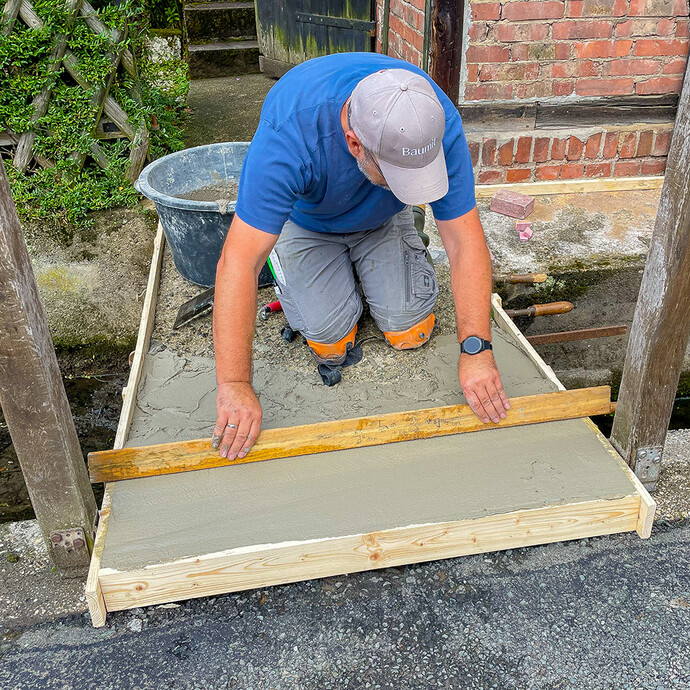 Abziehen des Gefällespachtels mit Abziehlatte entlang der Holzschalung.