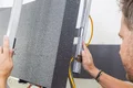 Heimwerker beim Anbringen einer Dämmplatte mit Richtschiene für präzisen Fassadeneinbau.