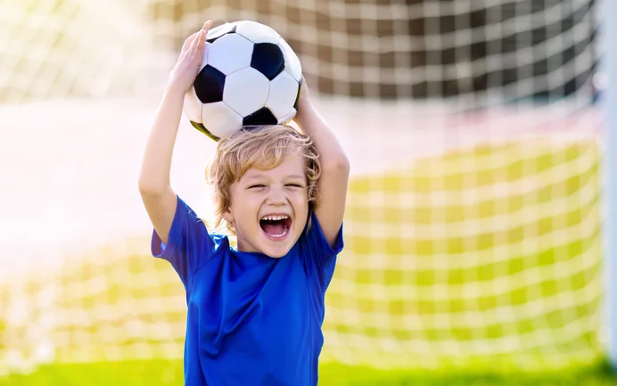 mit Fußball spielendes Kind auf einer Wiese
