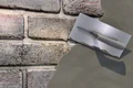Kelle beim Verputzen einer Backsteinwand mit faserverstärktem Dekorputz von Baumit. Ideal für Innen- und Außensanierung.
