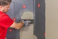 Person verputzt Wand mit Spachtelmasse, Dämmschutz sichtbar, Schritt für Schritt Anleitung für Heimwerkerprojekte von Baumit.