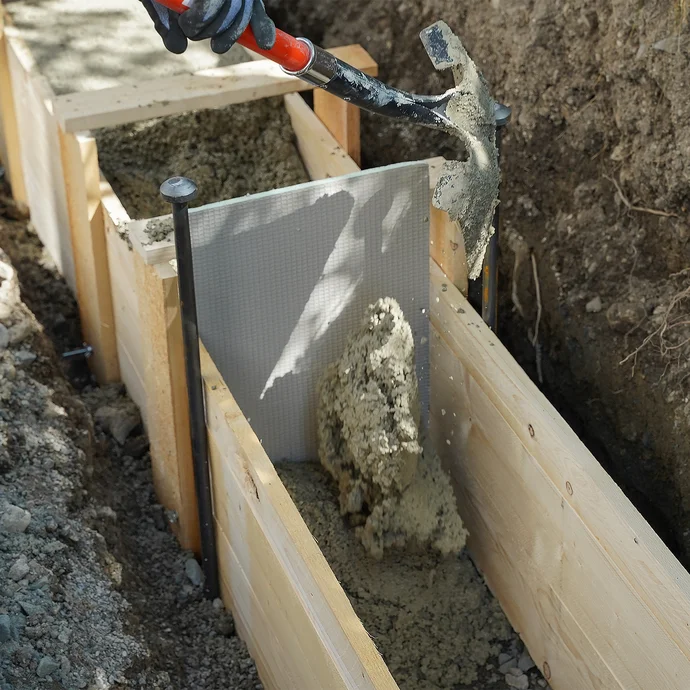 Beim Betonieren im Bereich der Dehnfuge wird der frische Trockenbeton vorsichtig mit der Schaufel von beiden Seiten eingefüllt, um ein Verrutschen der UniPlatte zu vermeiden.