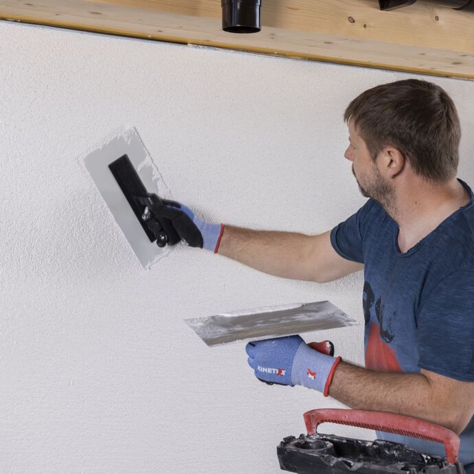 Person strukturiert den Putz mit einem Kunststoffreibebrett.