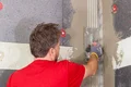 Heimwerker glättet Wand mit Spachtelmasse zur Vorbereitung auf Dämmung und Putzanbringung. Ideal für Renovierungsprojekte.