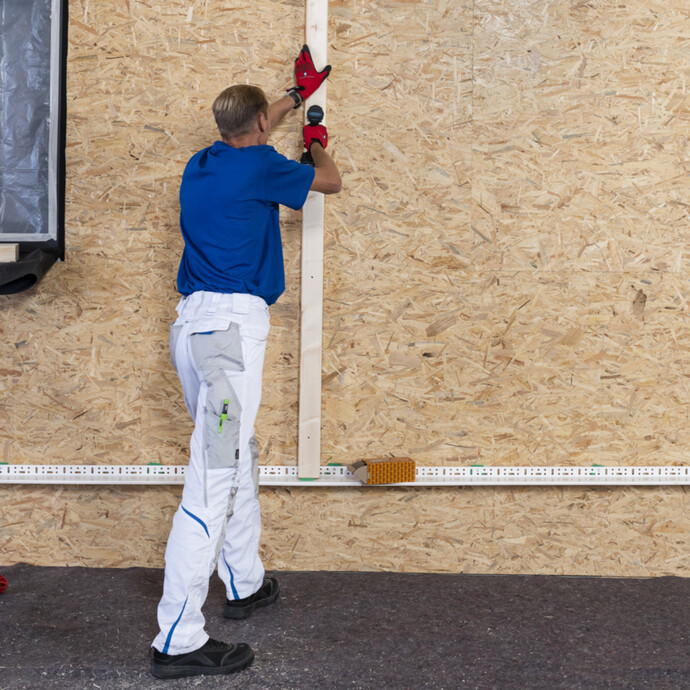 Erste Schraube als Befestigung des Tragholzes der Unterkonstruktion der Dämmfassade einschrauben.