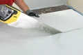 Heimwerker schneidet Gipskartonplatte mit Handsäge, vorbereitet für Innenausbauprojekt.