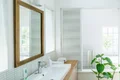 Modernes Badezimmer mit großem Spiegel, Waschbecken und Pflanzen, ideal für Heimwerker, die ihr Bad renovieren möchten.