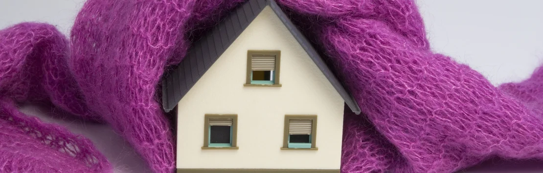 Miniaturhaus in rosa Decke symbolisiert effektive W&auml;rmed&auml;mmung.