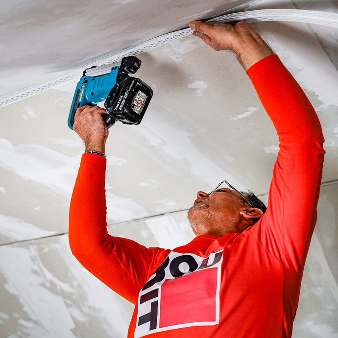 Le profilé de joint de dilatation est fixé le long du rayon laser à l'aide d'une agrafeuse.