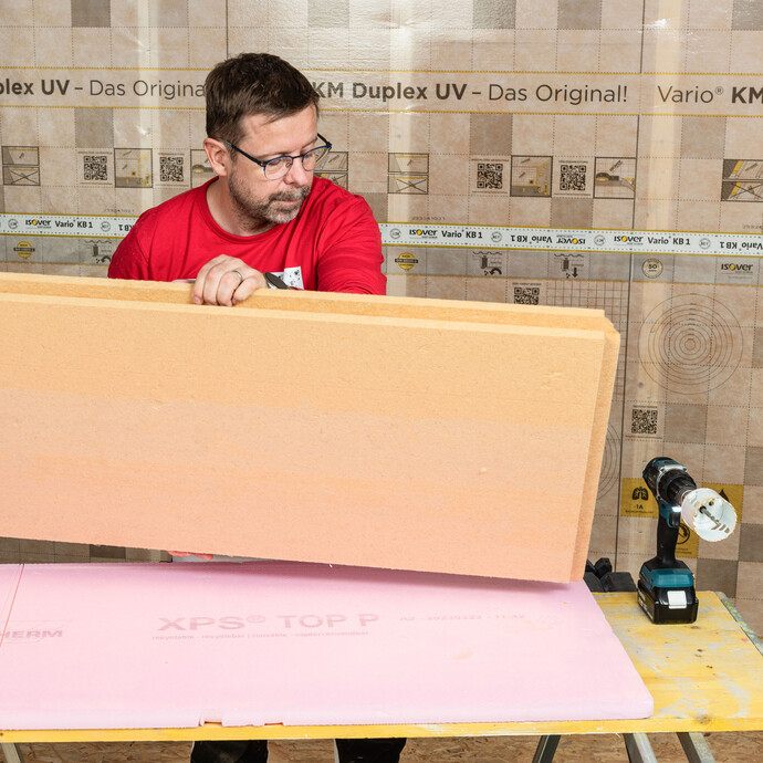 Der Heimwerker dreht die Holzfaserdämmplatte mit Nut und Feder um, sodass er ein Loch durch die Platte ohne Ausbrüche sauber aussägen kann. Tipp aus der Praxis für Heimwerker. Baumit Anleitung zum Selbermachen.