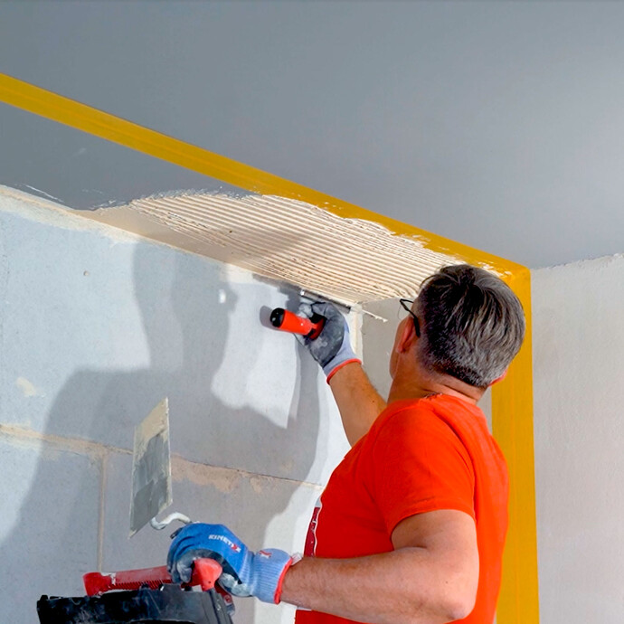 Heimwerker zahnt mit einer Traufel den frisch aufgetragenen Antischimmel 2 in 1 Putz auf.