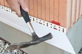 Handwerker befestigt einen Putzabschlussprofil an einer Hauswand. Ideal für saubere Kanten bei der Fassadensanierung.