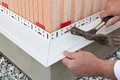 Montage eines Sockelprofils an einer Hauswand zur Vorbereitung der Dämmung.