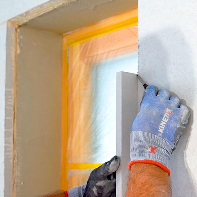 Person markiert sich die Grösse der Laibungsplatte, in dem sie die Platte in die Laibung setzt und den Überstand mit einem Bleistift markiert. So kann die Platte exakt zugeschnitten werden.