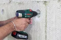 Heimwerker bohrt mit Akkuschrauber in Dämmstoffwand für Renovierungsprojekt.
