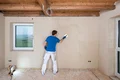 Heimwerker glättet eine verputzte Wand in einem Raum. Ideales DIY-Projekt für eine glatte, saubere Oberfläche mit Baumit.