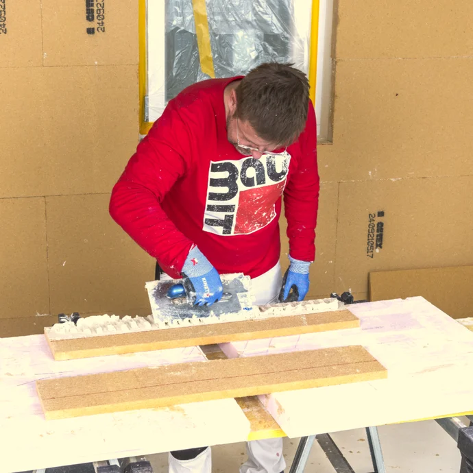 Un bricoleur applique de l'enduit sur un mur, le logo Baumit est visible. Instructions pour des travaux d'enduit à réaliser soi-même dans le cadre de projets de rénovation.