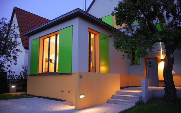 Einfamilienhaus mit orangenen Farbflächen und grünen Fensterläden für eine besondere Gestaltung
