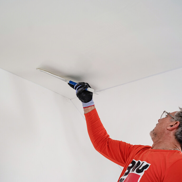 Der Rollspachtel wird mit einem Flächenspachtel abgeglättet.