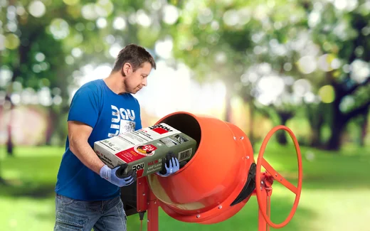 Heimwerker mischt Beton mit Betonmischer im Grünen; ideal für Bau- und Renovierungsprojekte.
