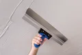 Hand glättet Putz an Decke mit Spachtelwerkzeug.