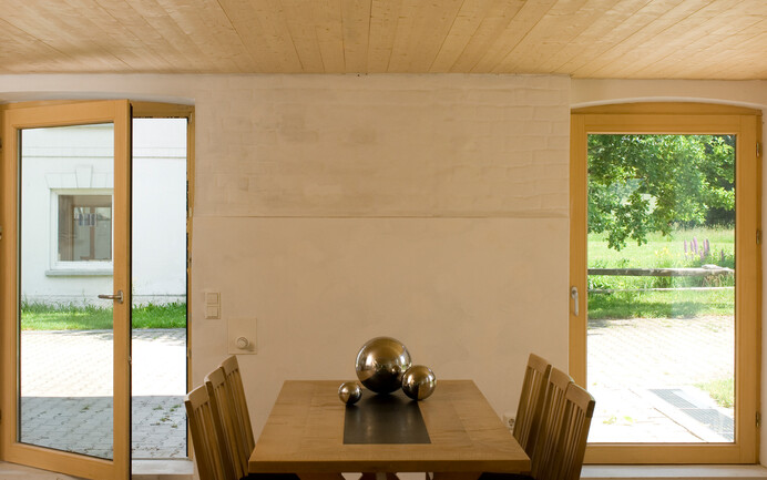 La salle à manger a été enduite d'un crépi d'argile Baumit et peinte dans des tons beiges. Le plafond en bois et les meubles confèrent à la pièce une atmosphère chaleureuse.